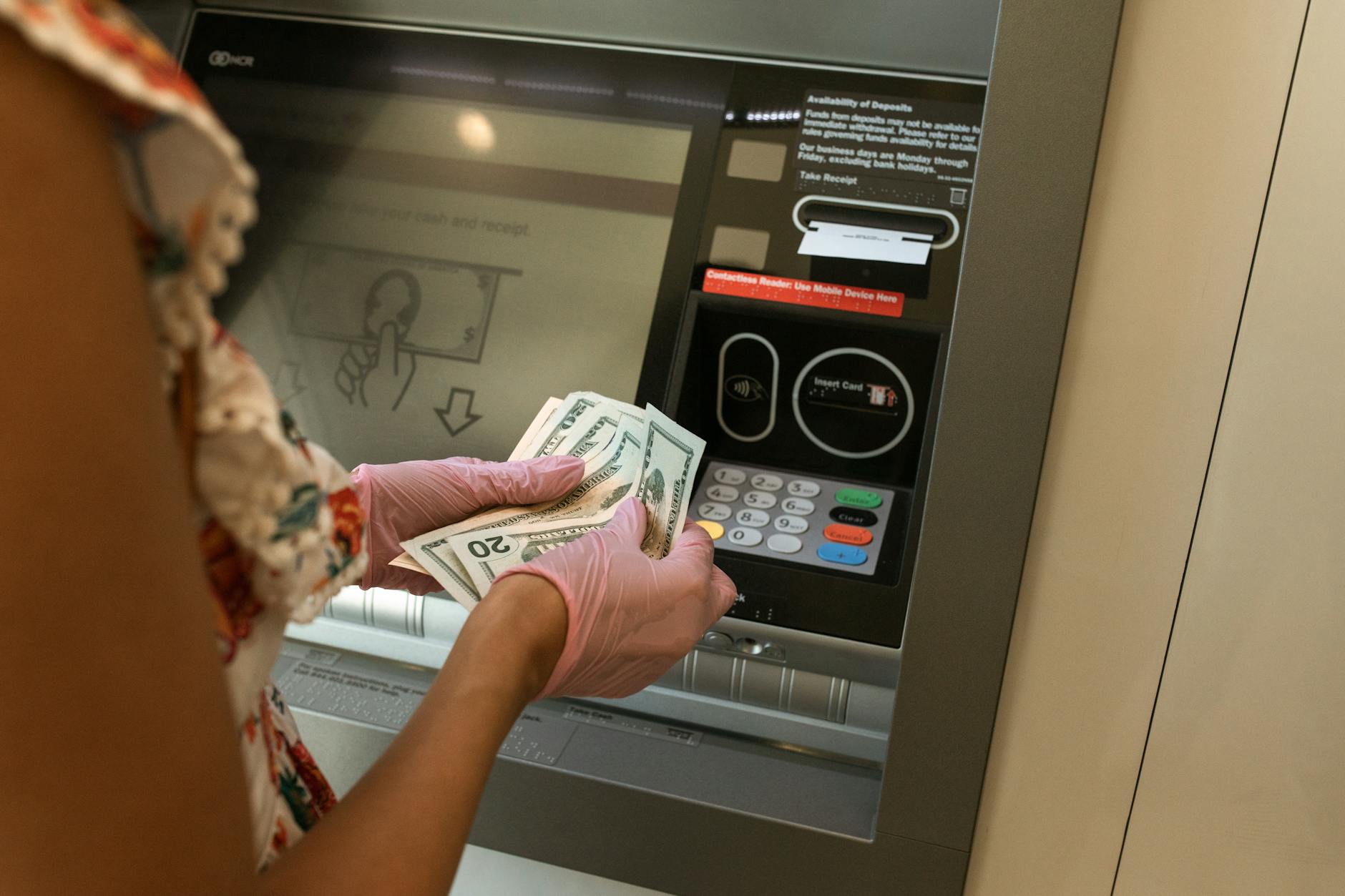 A customer handing a paper check across a bank counter, illustrating Regulation CC deposit holds and funds availability.