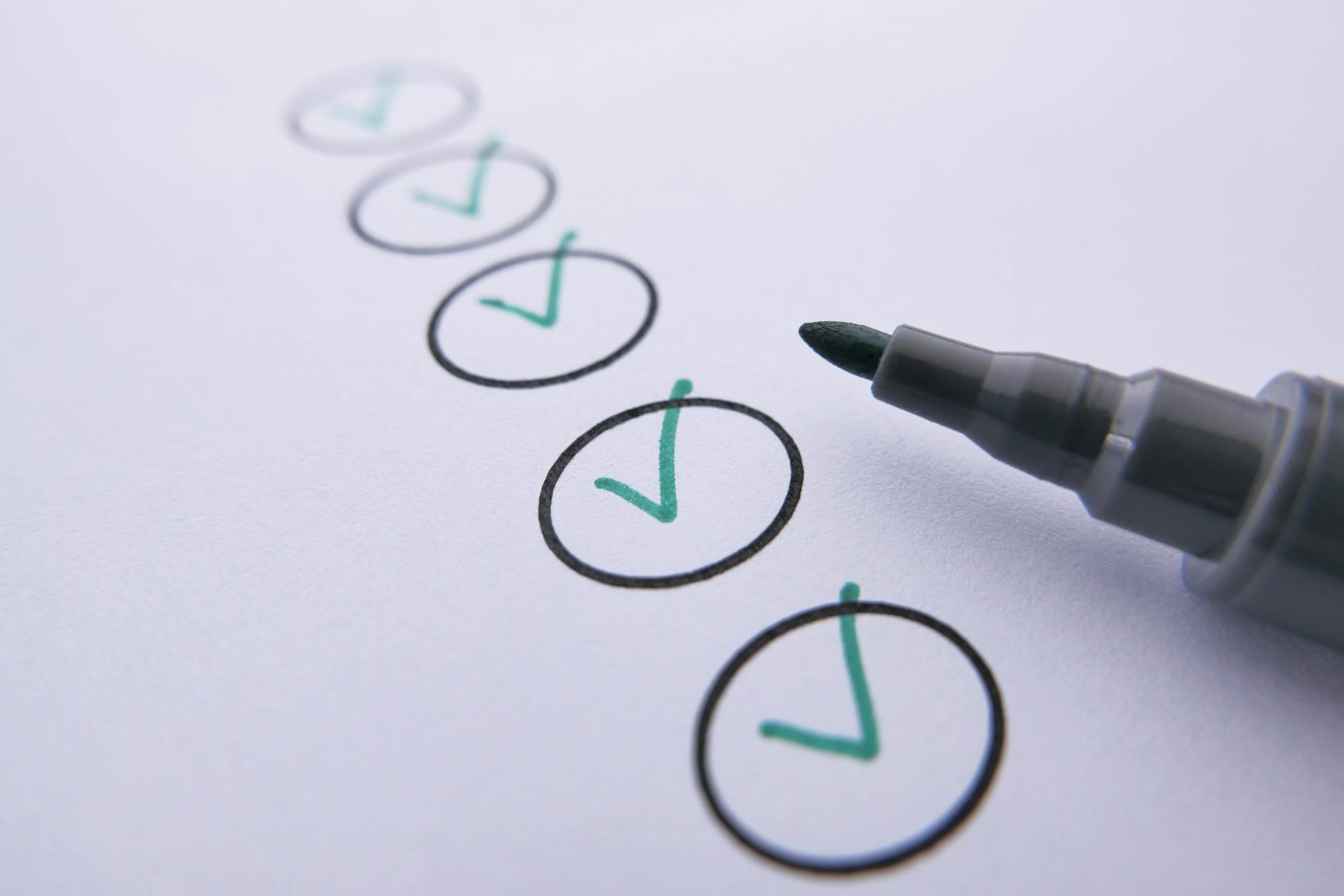 Person writing a paper check, showing routing and account numbers on the bottom edge