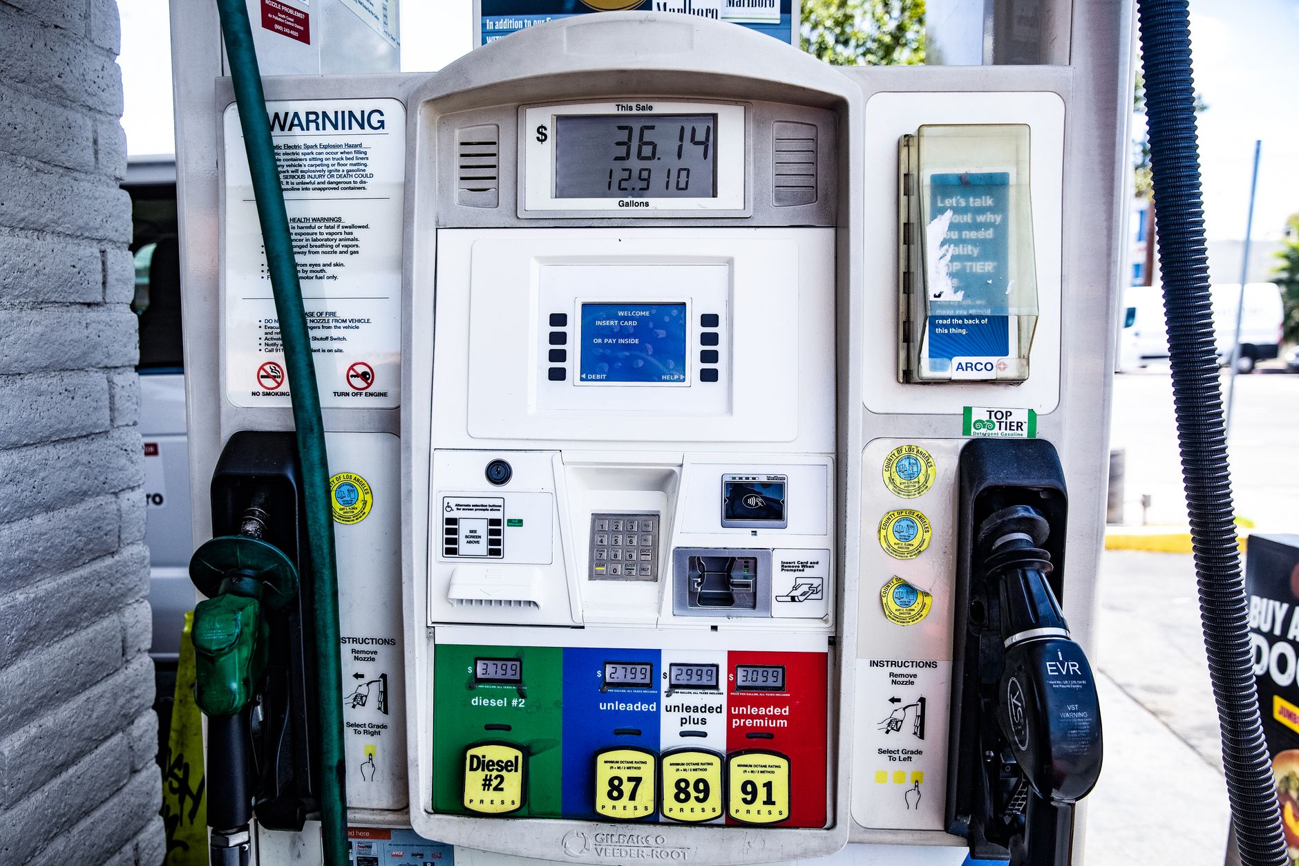 A driver paying at a gas station pump, where debit card authorization holds commonly occur