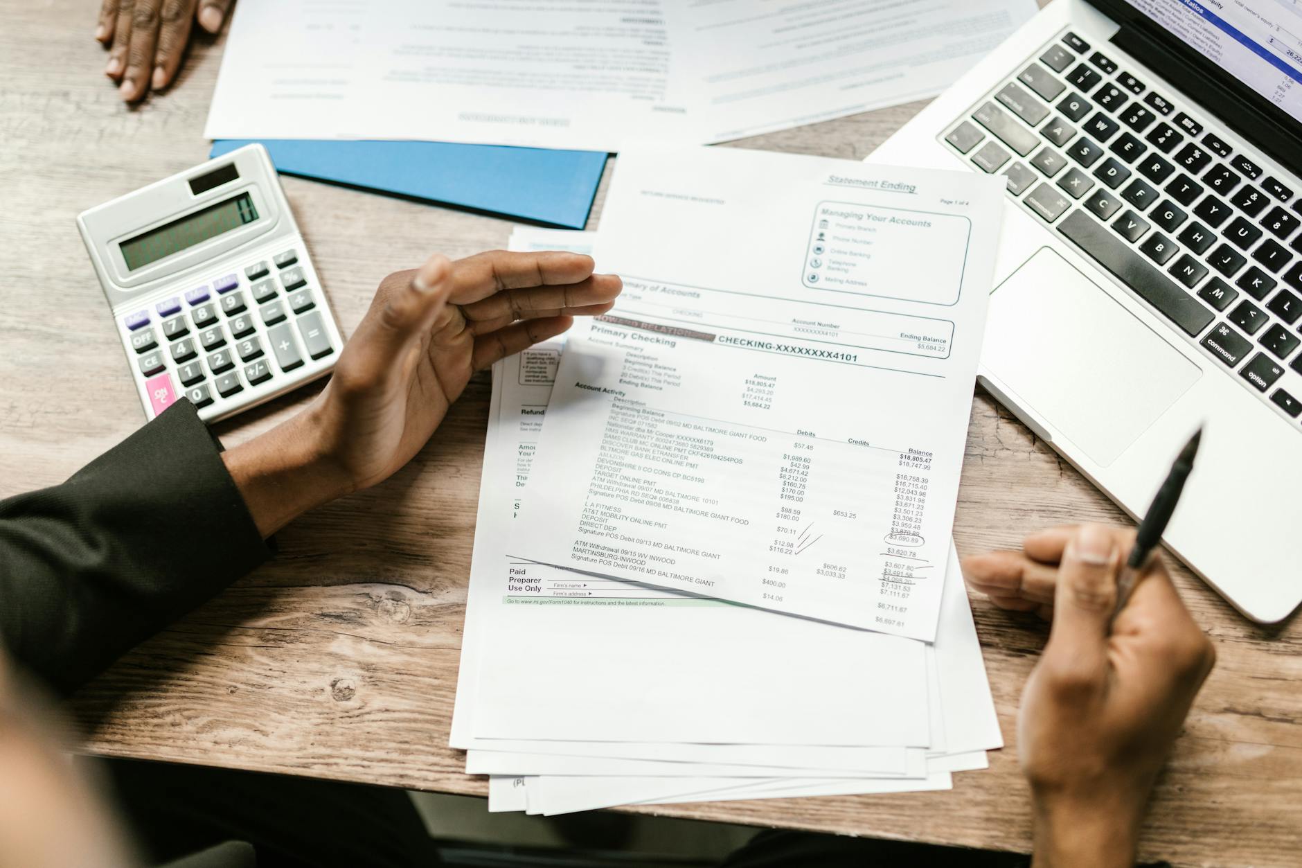 A person reviewing financial accounts on a laptop with a calculator, illustrating the difference between money market accounts and money market funds