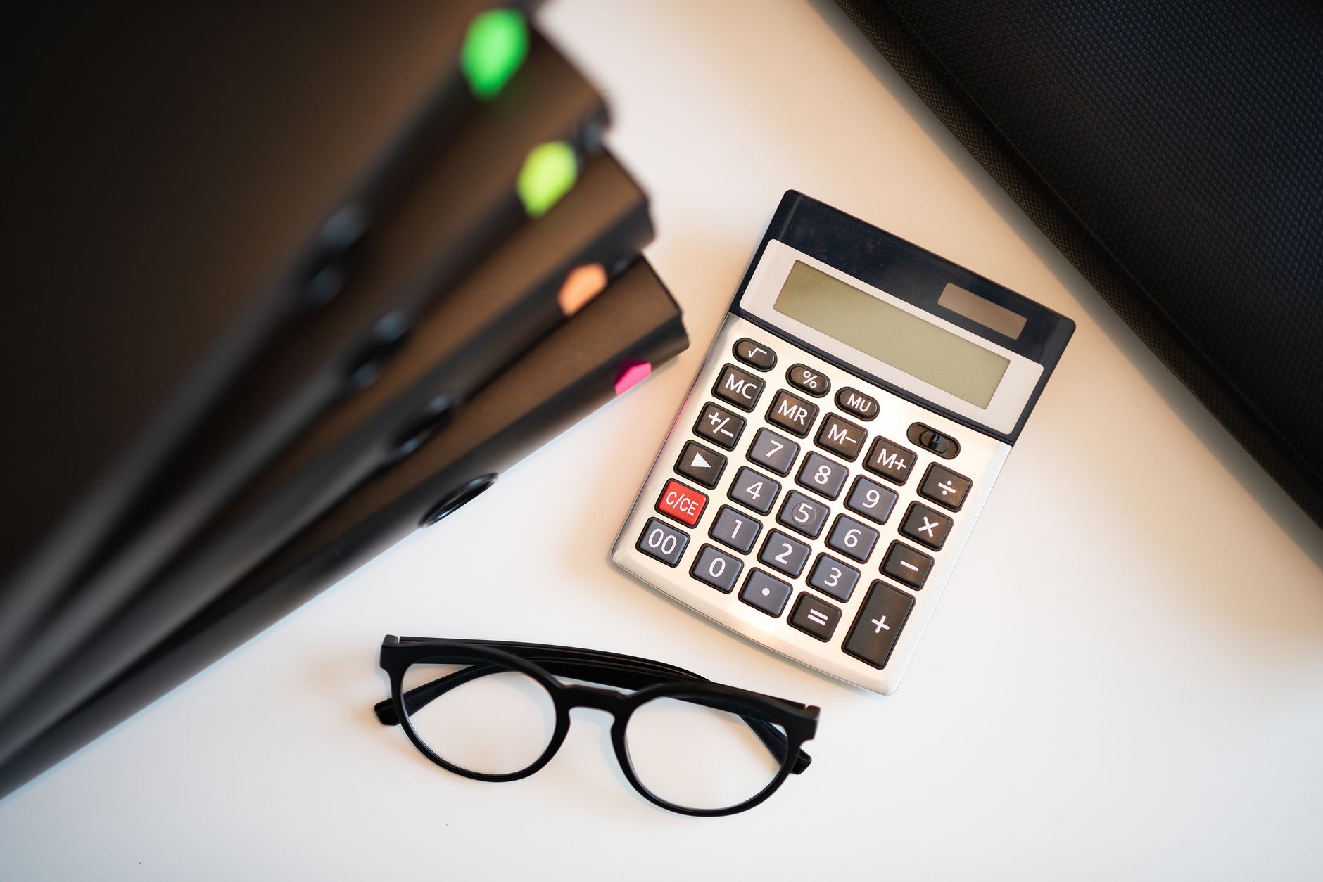 Person calculating personal finances with a calculator and documents at a desk