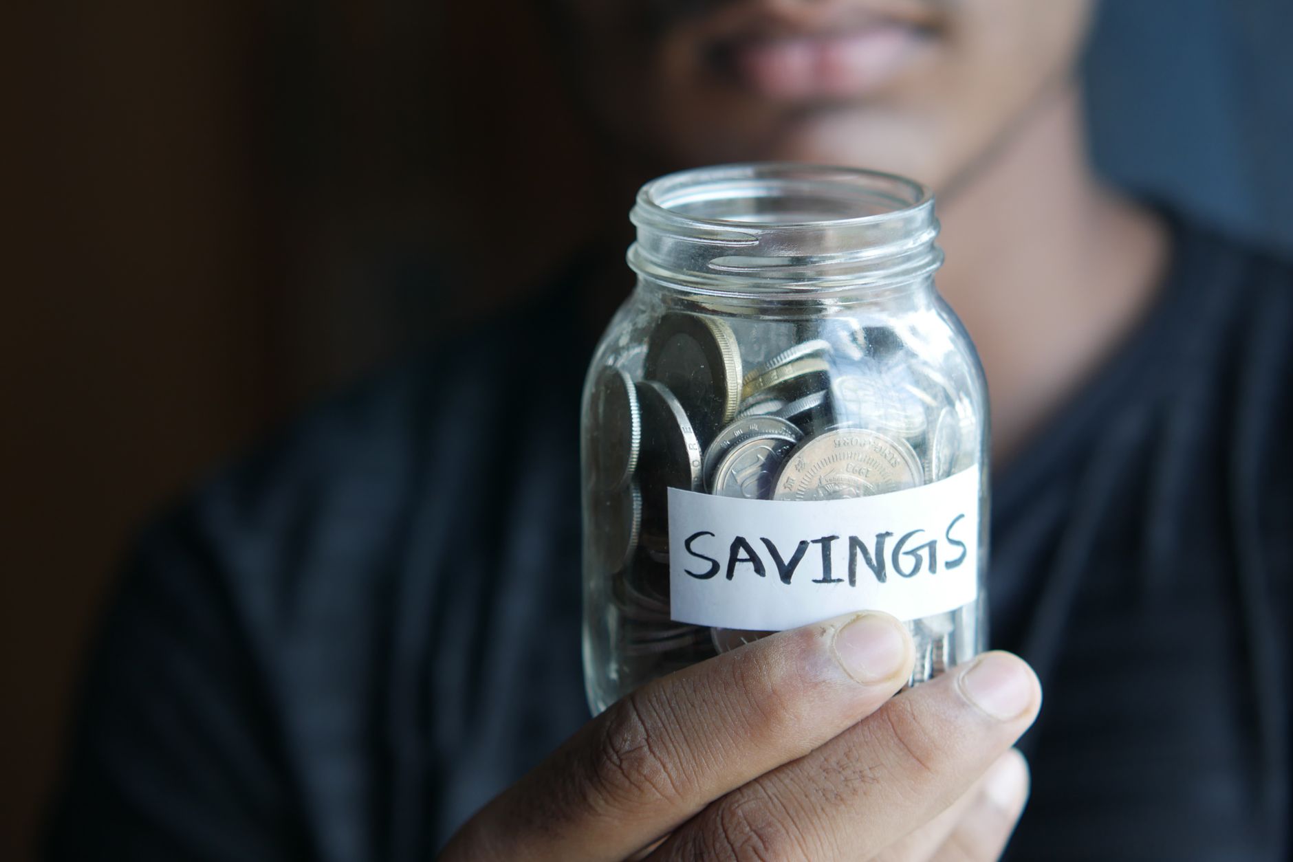 Coins in a savings jar next to growing stacks representing saving and investing