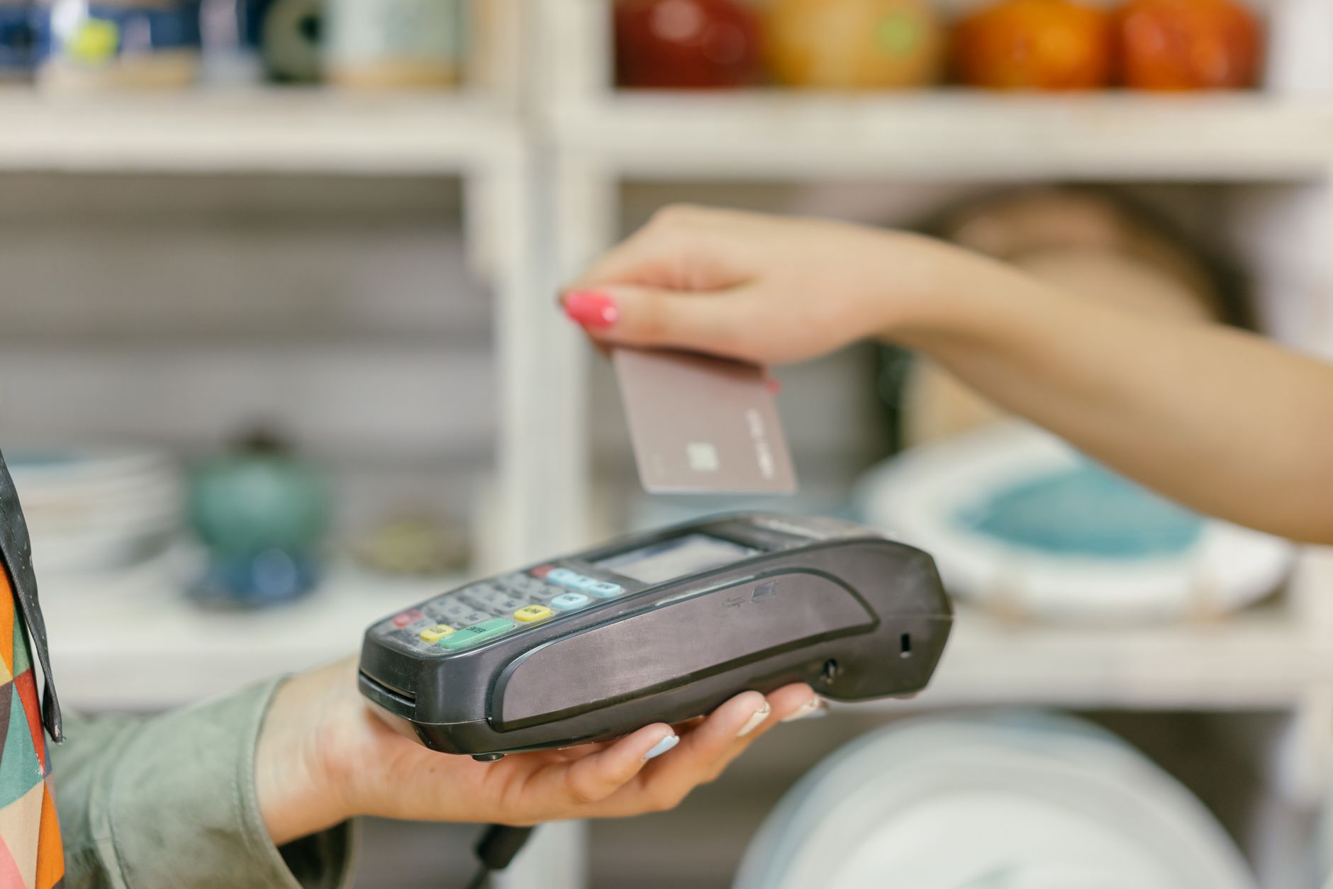 Customer tapping a credit card on a payment terminal at a store checkout