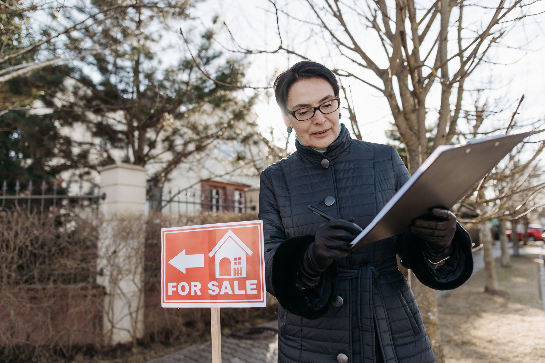 A for sale sign in front of a suburban house on a residential street