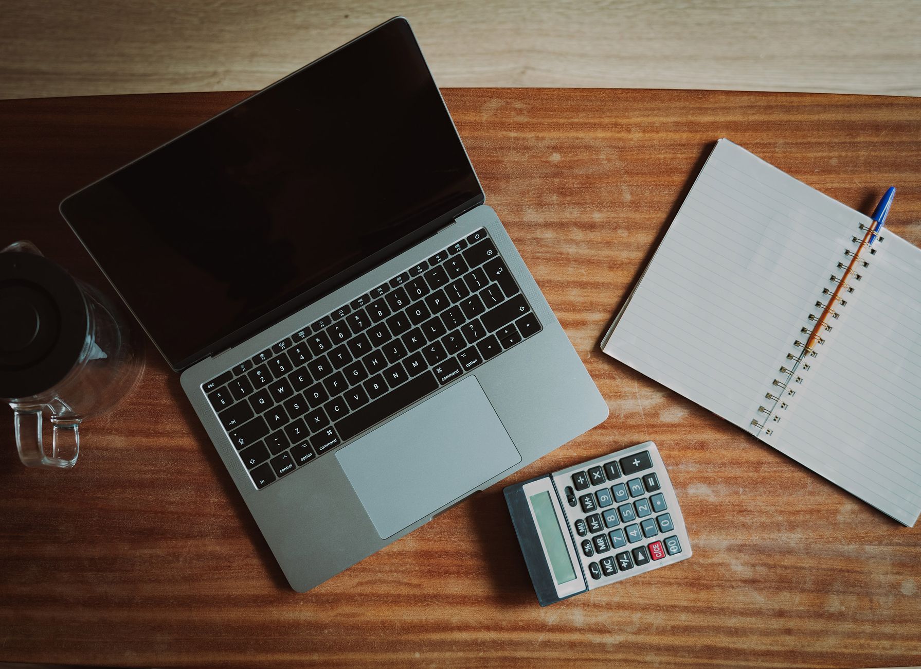 Payroll documents and a calculator on a desk while reviewing a pay stub