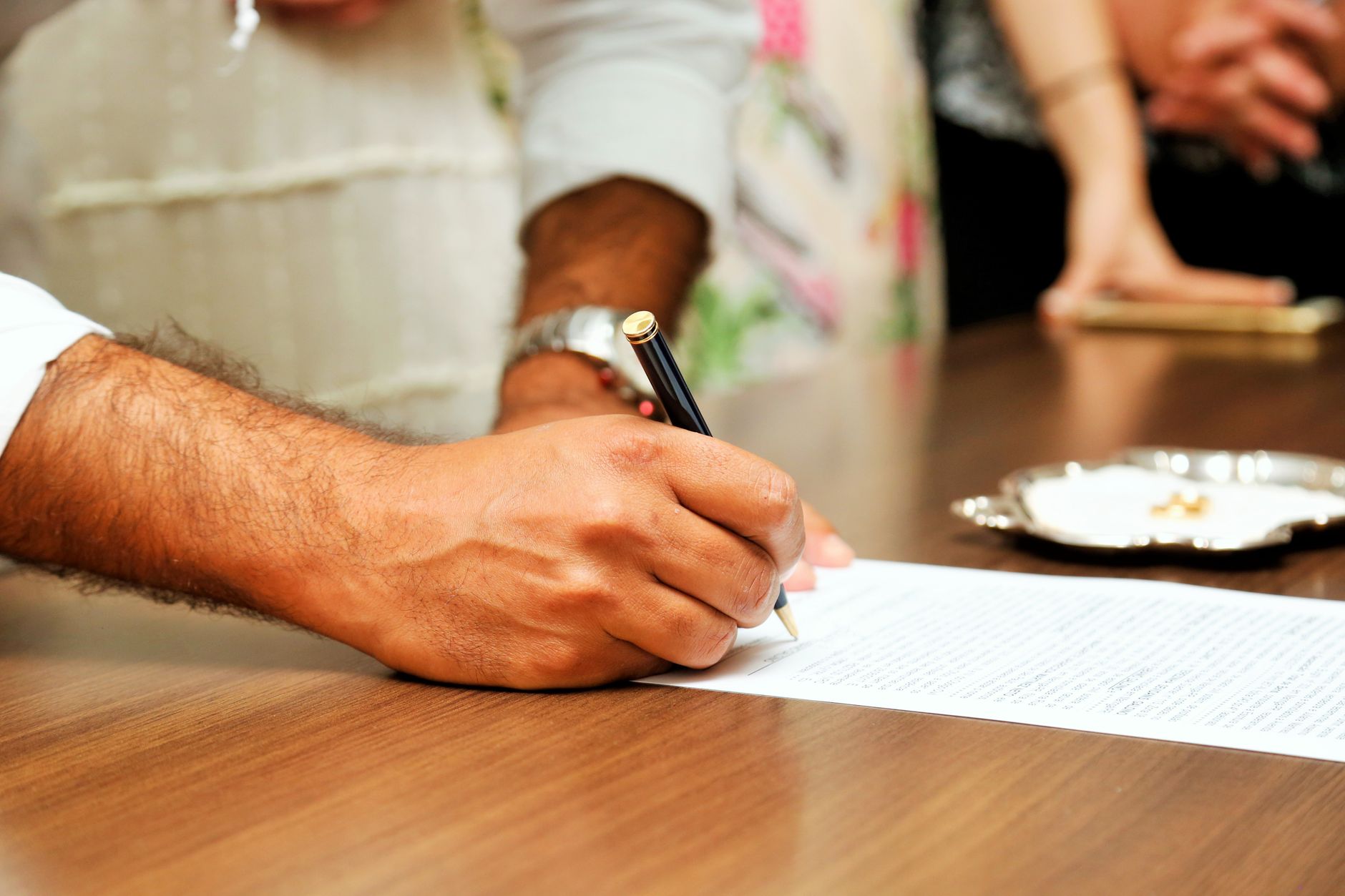Person signing a legal document at a desk with a pen