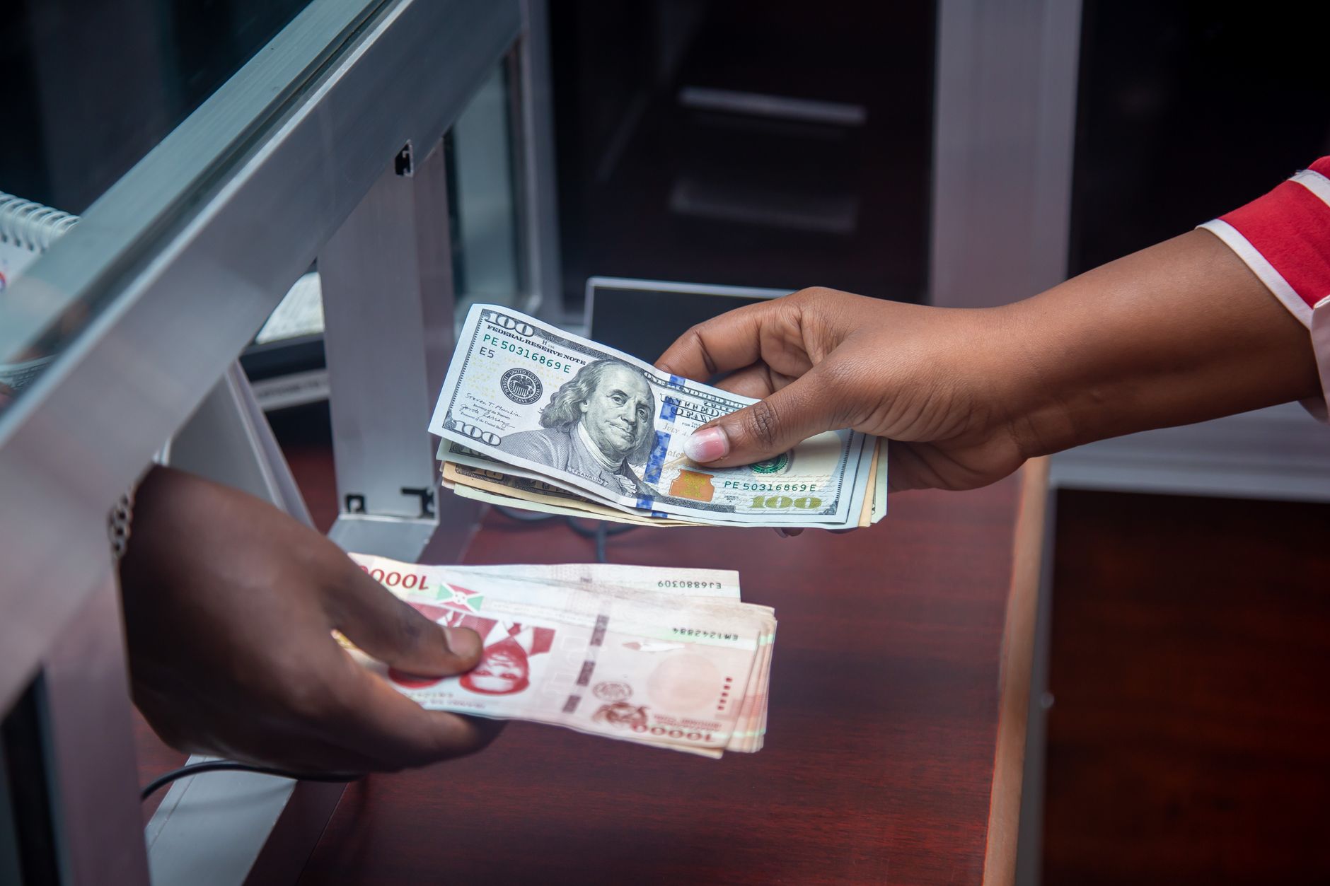 Two people exchanging cash across a counter during a banking transaction