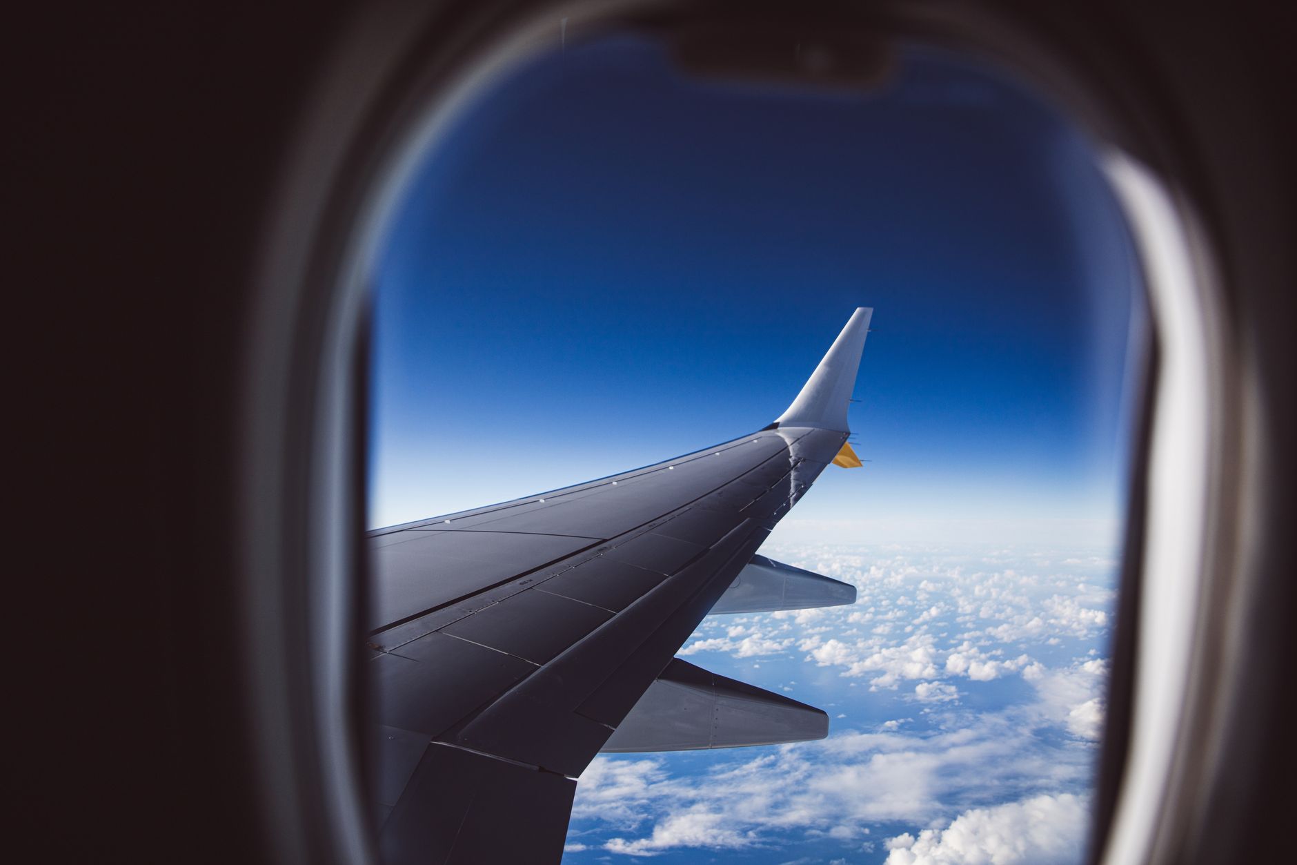 View of an airplane wing above the clouds from a passenger window
