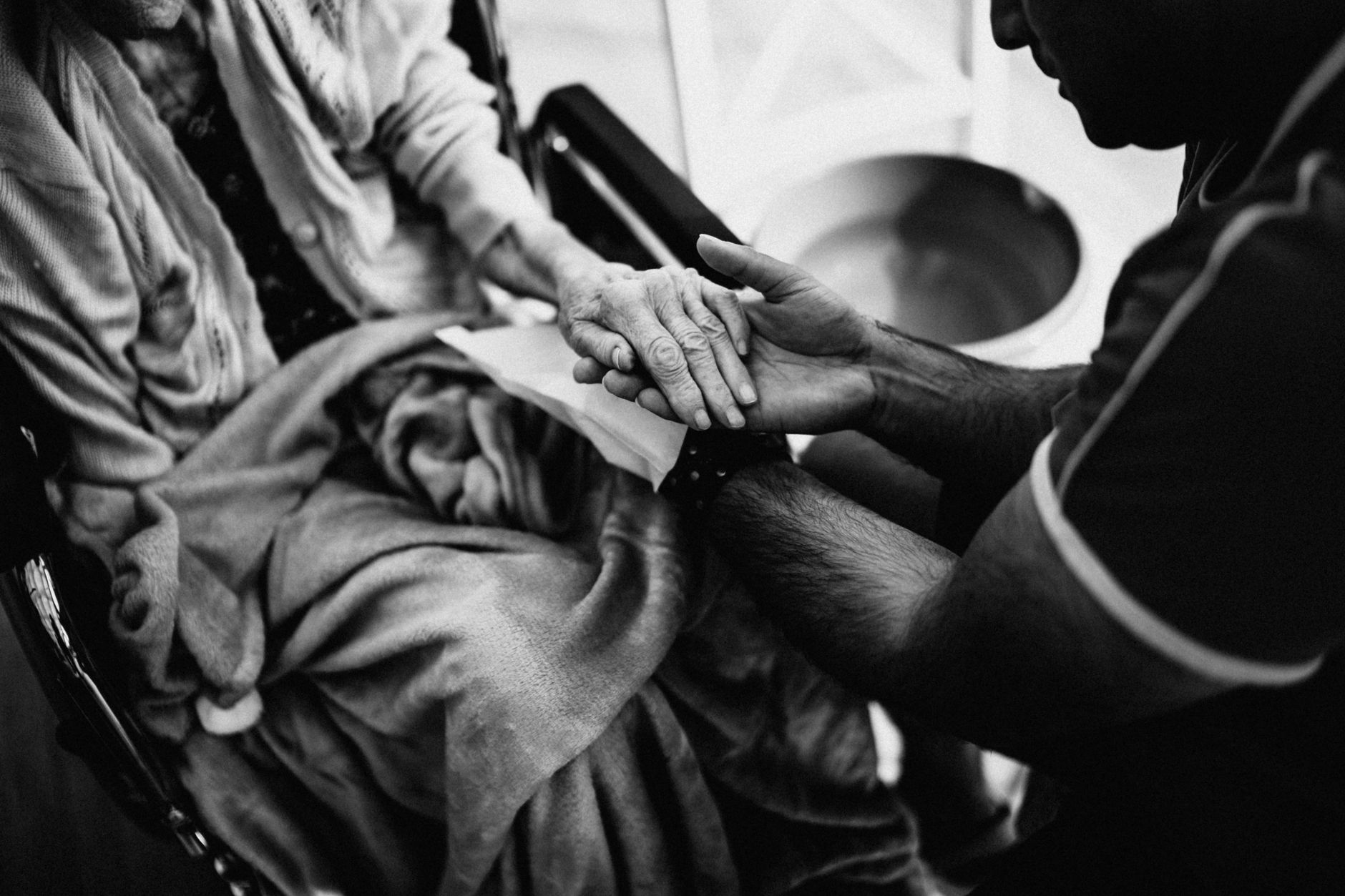 A caregiver holding the hands of an older woman at home