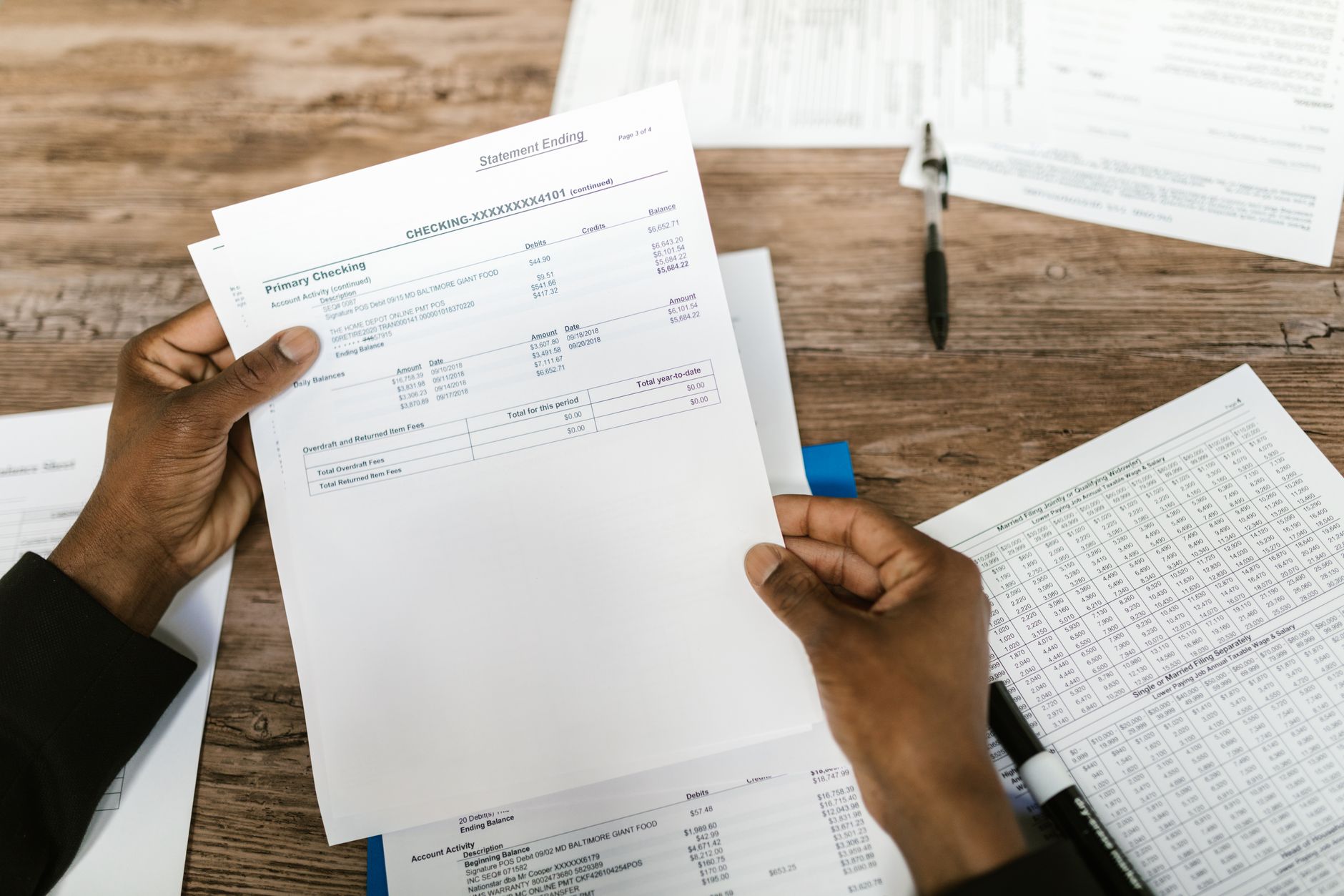 Person reviewing a printed bank statement at a desk