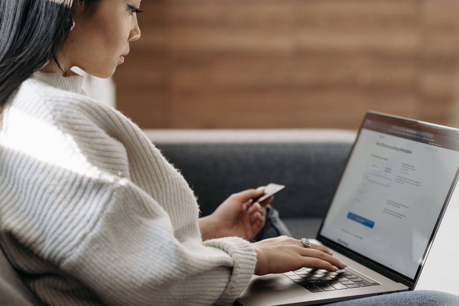 Person paying bills online with a laptop and paper bills on a desk